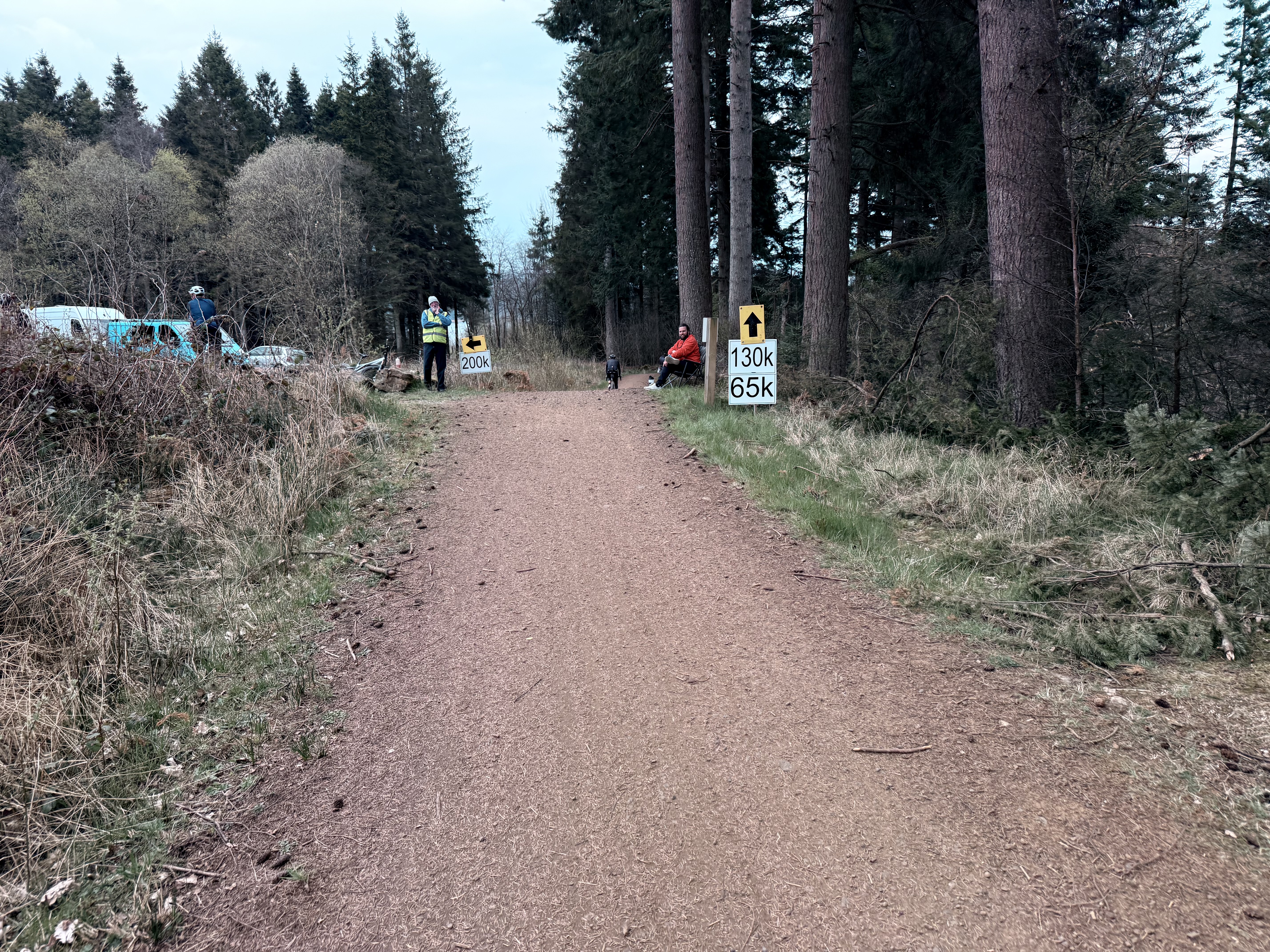 A photo showing a split in a forest trail. One way is signposted 130k, the other 200k